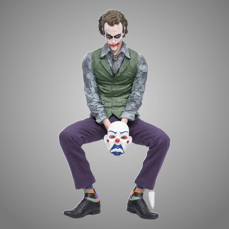 The Joker sitting statue holding a clown mask, 15 cm PVC collectible figure on gray background